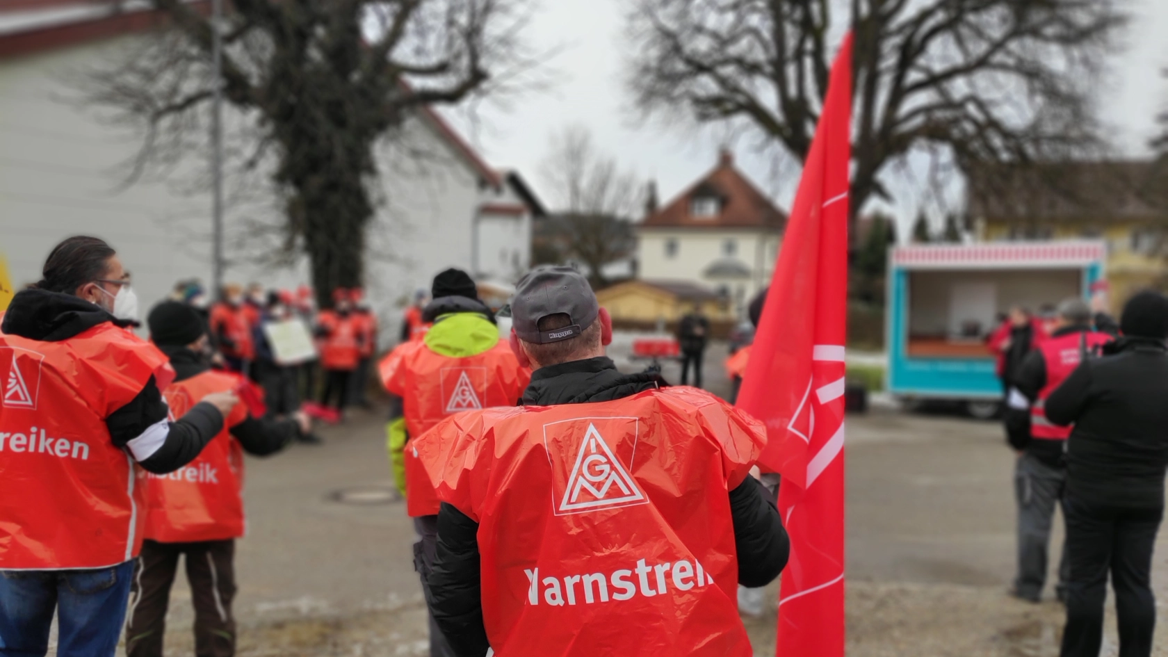 Ein Streikender mit Fahne beim Warnstreik bei Alzmetall