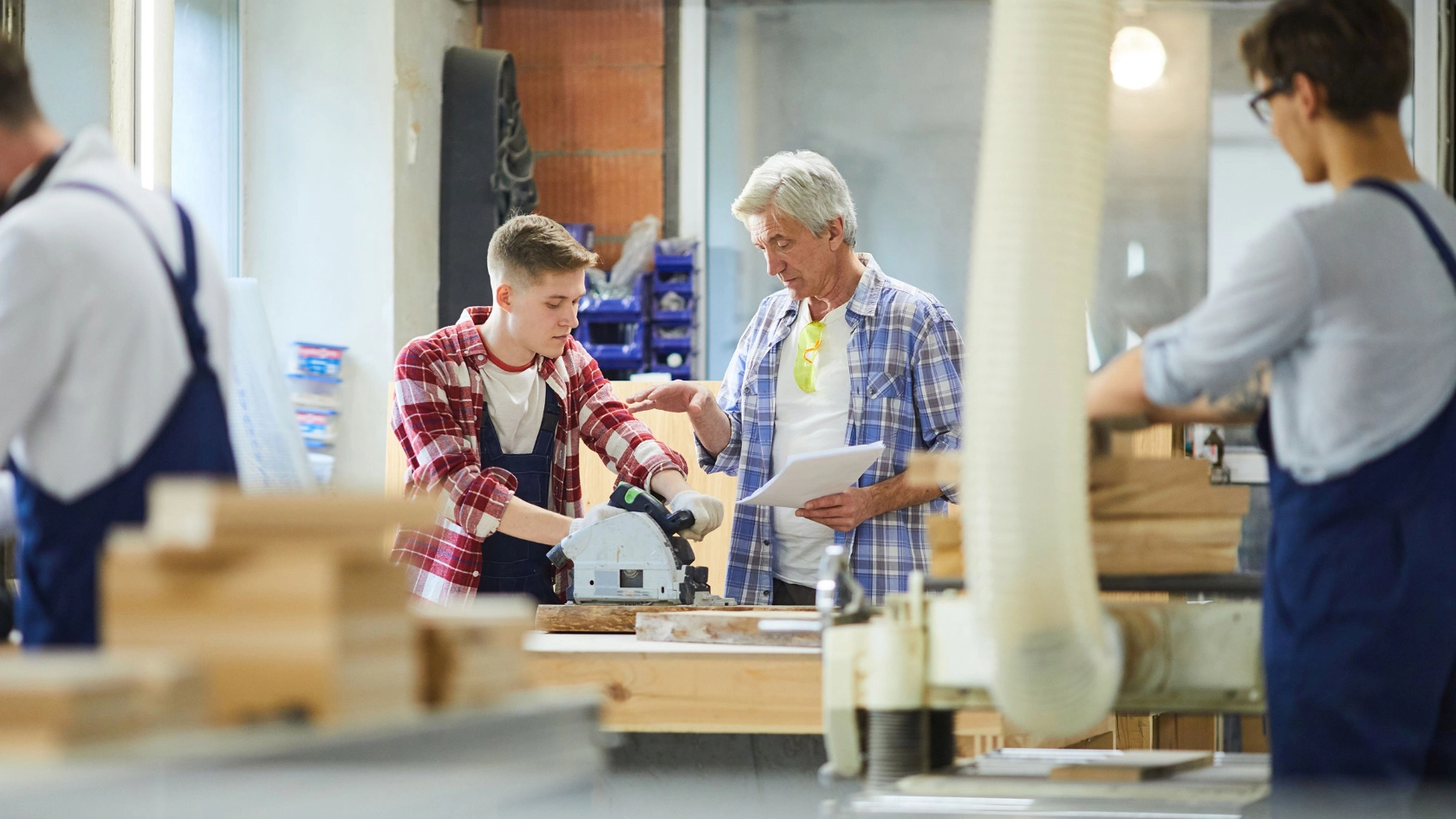 Auszubildender und Meister im Gespräch in einer Schreinerwerkstatt