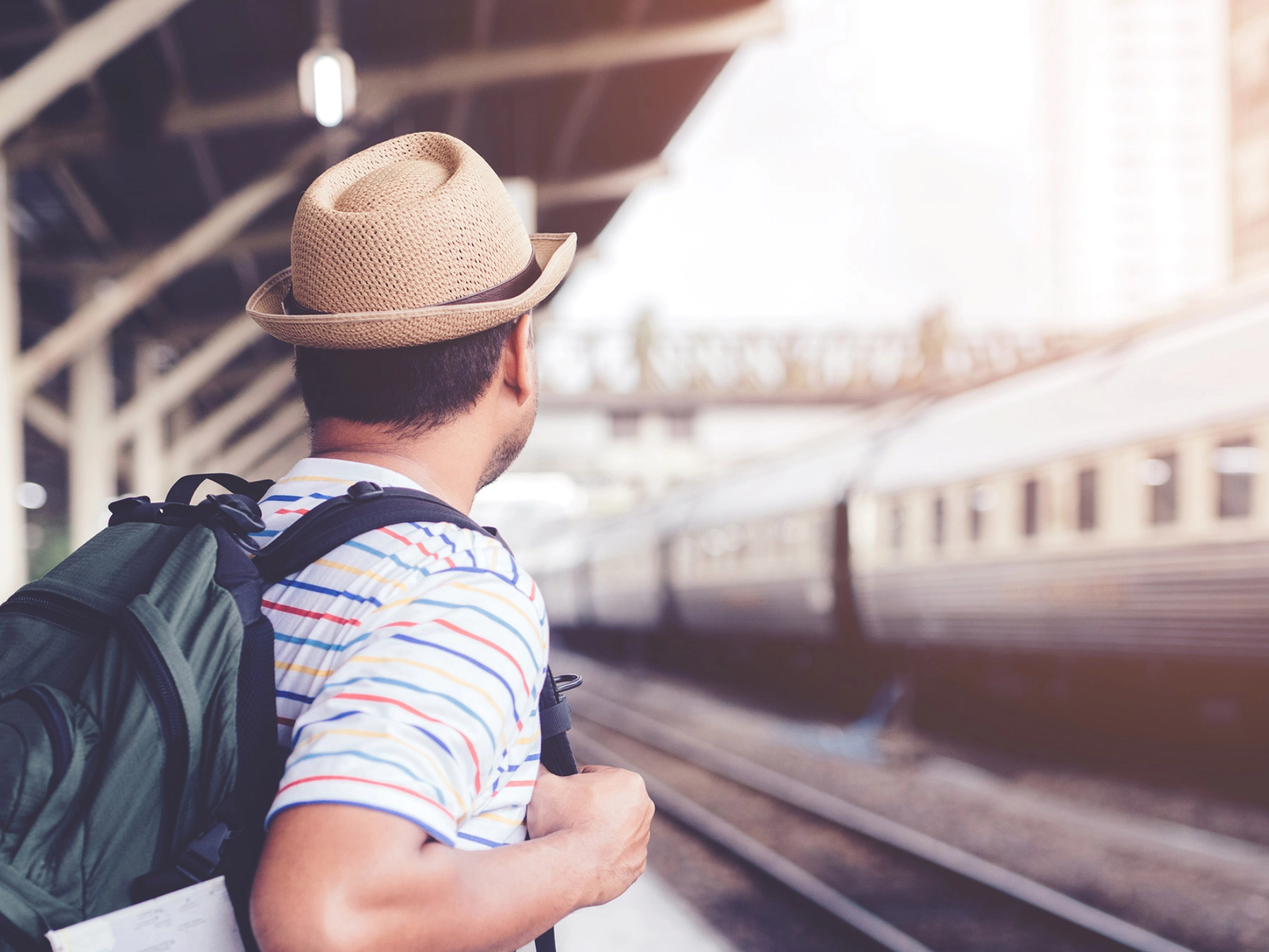 Junger Mann mit einem Rucksack warten auf dem Zug 